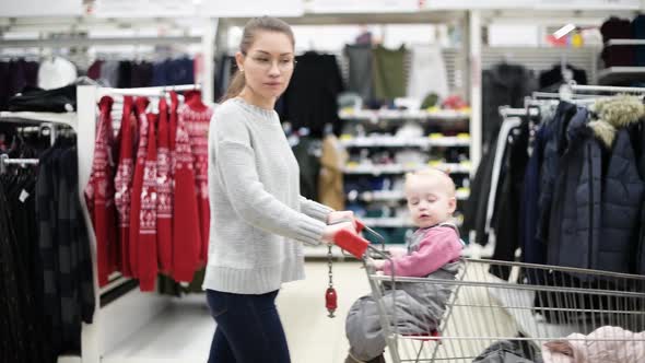 young mother with a small daughter walks in the clothing department in a supermarket