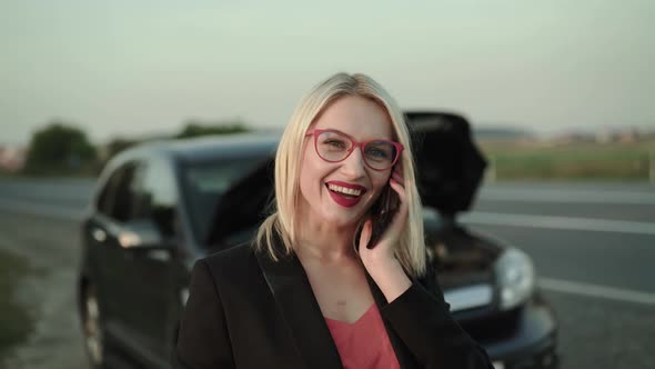 Beautiful Blonde Receives the Call and Talks Near a Broken Car at the Terrace