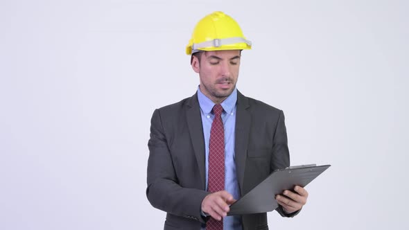 Young Hispanic Businessman As Engineer Reading on Clipboard and Directing