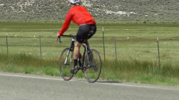 A man road biking on a scenic road.