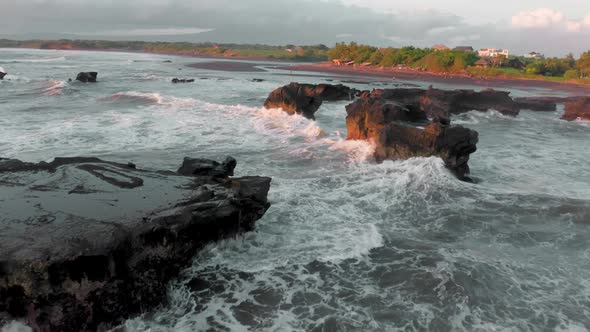 A Beautiful Bird'seye View of Flying Around the Black Rocks on Ocean at the Golden Hour