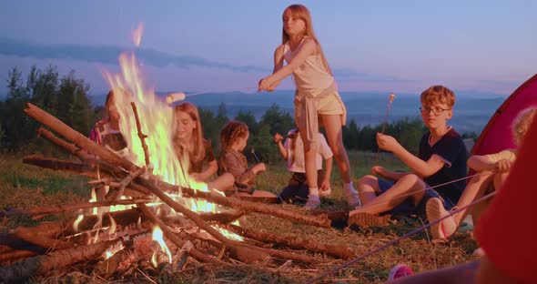 Group of Children Sitting Around Fire at Twilight