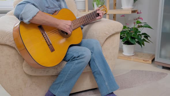 Senior Man Plays Acoustic Guitar and Sings in Apartment Living Room