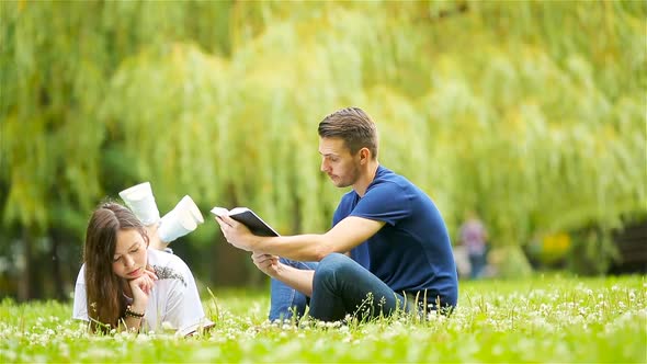 Relaxed Young Couple Reading Books While Lying on Grass