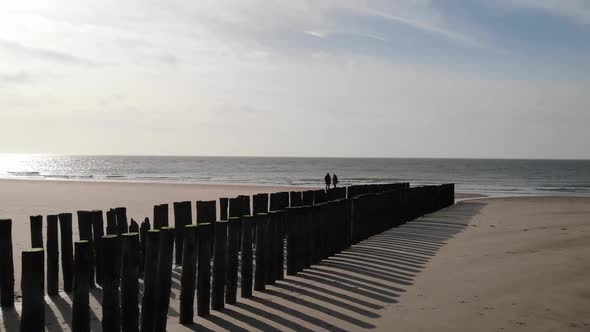 Couple walking on the beach in autumn or winter. Horizon and sea. Dolly shot