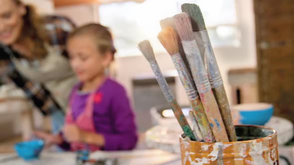 Mother assisting her daughter in painting a bowl