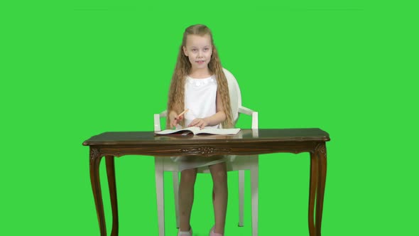 Cute Little Girl Doing Homework, Writing Down on a Green Screen, Chroma Key