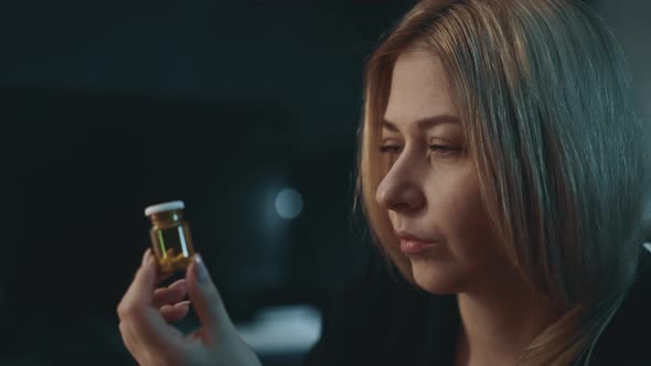 Suspicting Woman Holds Pill Bottle on Blurred Background