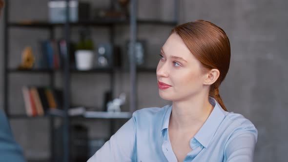 Young woman in a suit listening to a corporate manager at a meeting