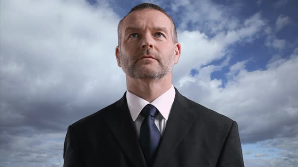 Businessman looking at camera with cloud and sky background, portrait