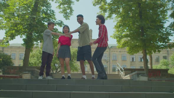 Cheerful Diverse Multiracial College Students Making Pile of Hands at Campus