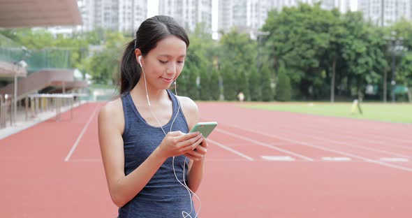 Sport woman listen to music on cellphone in sport arena