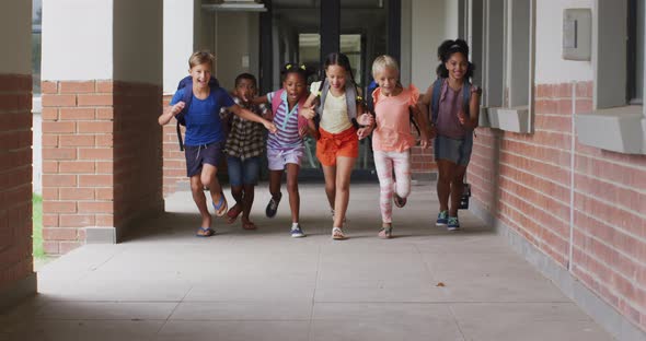 Video of happy diverse pupils running on school corridor