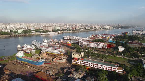 Aerial: dockyard at Buriganga river bank with city landscape in Dhaka, Bangladesh - drone establishi