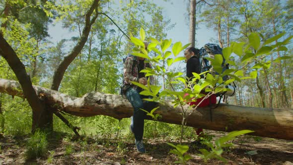 Backpackers Taking a Break During Hike Sitting on Tree Trunk in Nature