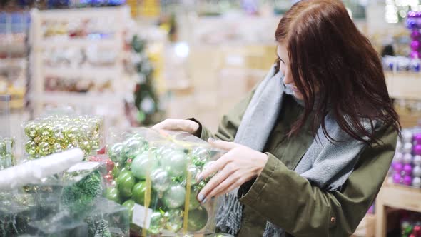 A Young Beautiful Woman Walks Around the Store and Selects Christmas Decorations and Decorations to