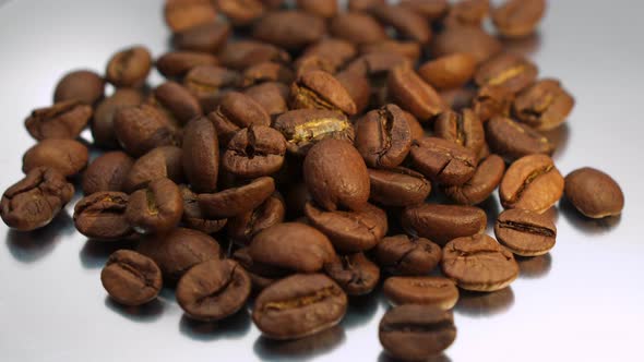 Roasted coffee beans rotate on white background. 	