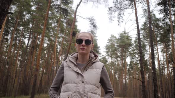 Portrait of a Beautiful Young Woman in Waistcoat and Sunglasses. Pine Tree Forest 