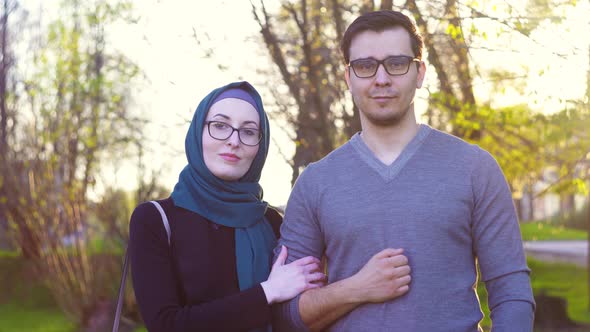 Cute Young Couple in Glasses Looks at Camera in Park Sunny