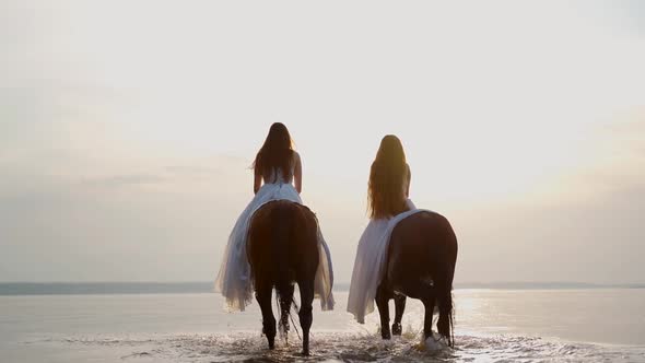 Two Beautiful Girls in White Long Dresses on Horseback