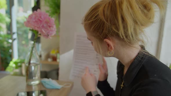 Young Woman Choosing From Menu In Cafe In Prague