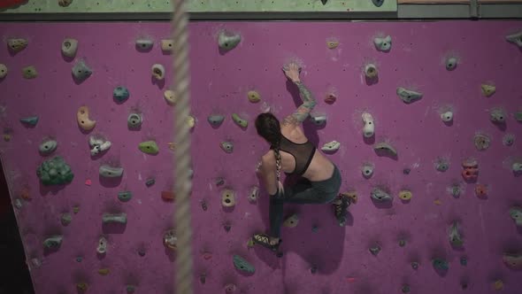 Fit Girl Climbing Artificial Rock Wall with Detail of Climbing Rope
