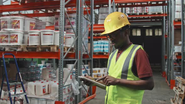 Black Male Warehouse Worker Typing on Tablet