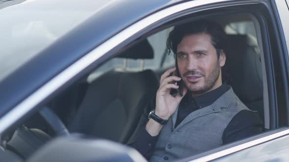 Successful Intelligent Businessman Talking on Phone Sitting on Driver's Seat in Luxurious Car