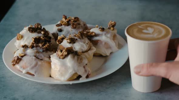 Latte leaf design in cup next to fresh icing buns serving cappuccino closeup with 4k