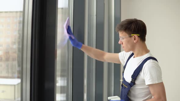 Young Cleaner in Protective Uniform Washes Windows