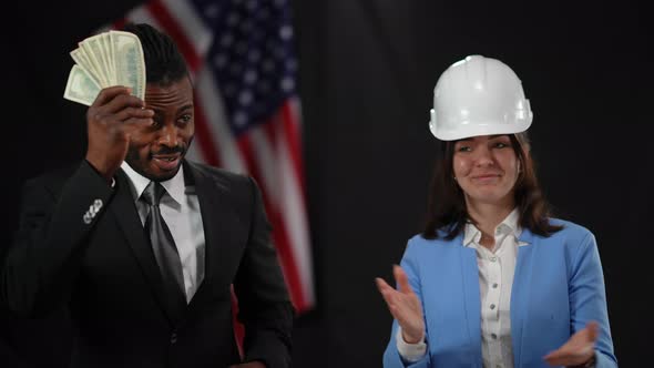 African American Male Politician Passing Cash Money to Caucasian Woman in Hard Hat in Camera Flashes