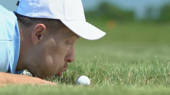 Man Blowing Golf Ball Into Hole and Rejoicing, Breaking Rules, Joke, Close-Up