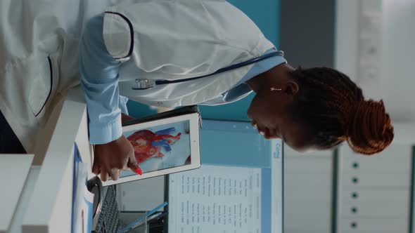 Vertical Video Doctor Pointing at Cardiology Figure on Digital Tablet