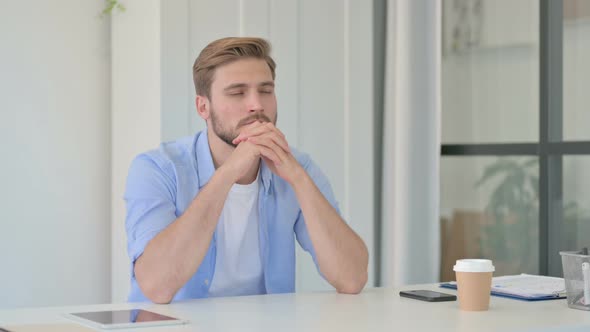 Pensive Young Creative Man Sitting in Office Thinking