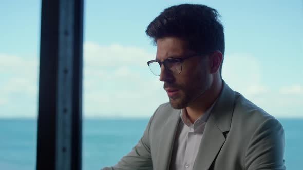 Focused Man Reading Papers at Sea Panorama Window Closeup