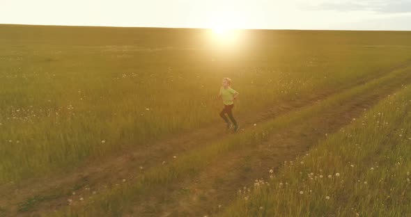 Sporty Child Runs Through a Green Wheat Field. Evening Sport Training Exercises at Rural Meadow. A