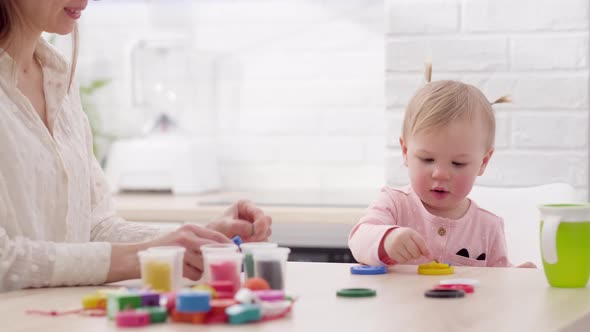 Mom and Little Daughter Sitting in Kitchen and Playing Multicolored Plasticine Mother and Daughter