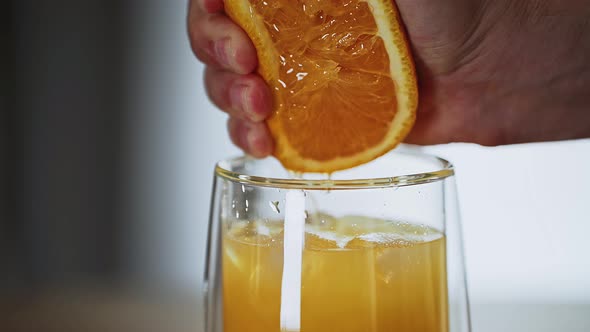 man squeezes orange juice into a glass. refreshing drink. citrus fruit. fresh juice