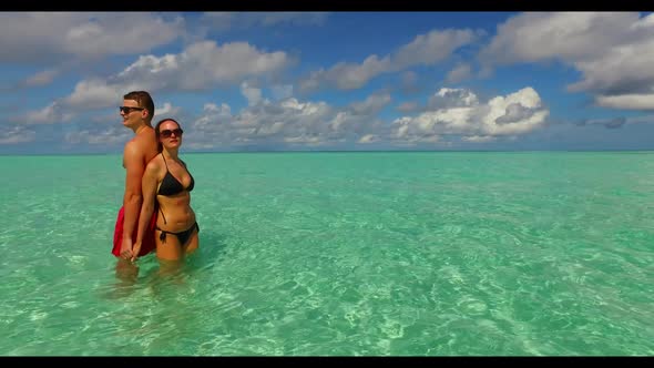 Guy and girl happy together on tranquil coast beach time by blue sea with bright sand background of 