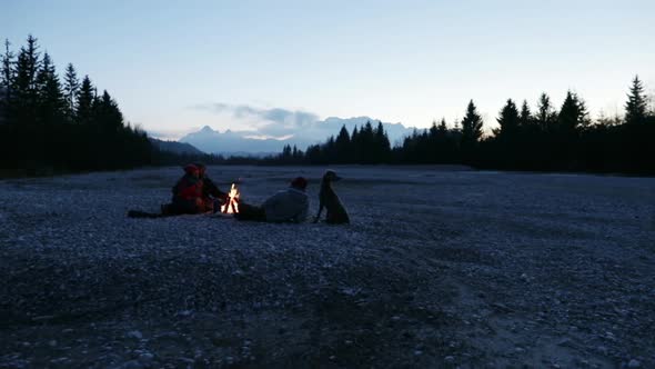 Group of friends sitting at a bonfire at dawn