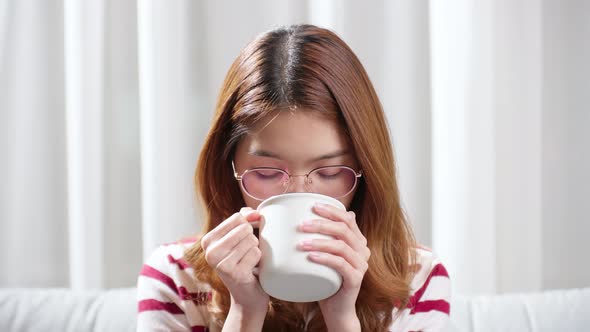 Asian young woman on a cold day drinking a hot cup of tea to relax.