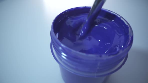 Man Holds Brush in His Hand Ready To Paint with Blue Paint. White Background. Draw the Picture