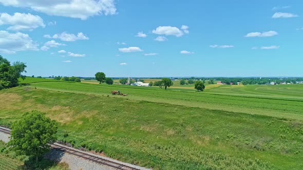 Aerial View of an Amish Farmer with Three Horses Harvesting His Crops