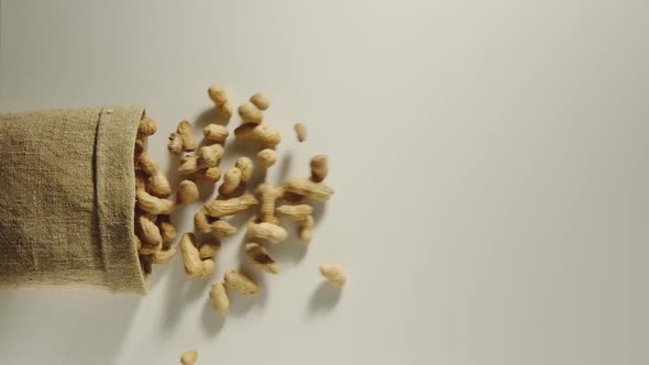 Bag Falls And Unpeeled Peanuts Are Poured Out Of It On White Background