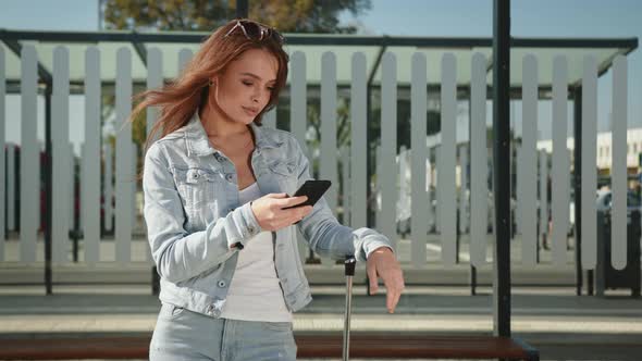 A Young Woman is Standing at a Public Transport Stop