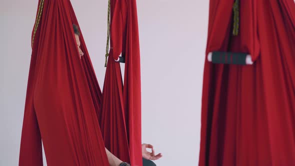 Group Sits in Butterfly Position in Fly Yoga Hammocks