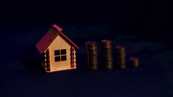 Small Wooden House with Columns of Coins on Black Background