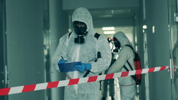 Disinfection Worker is Taking Notes in a Corridor