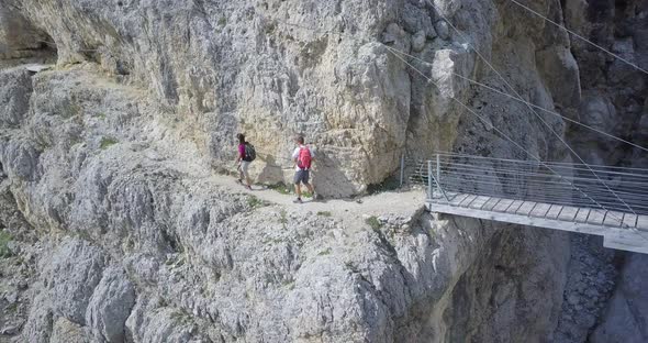 Aerial drone view of a man and woman couple hiking a bridge in the mountains