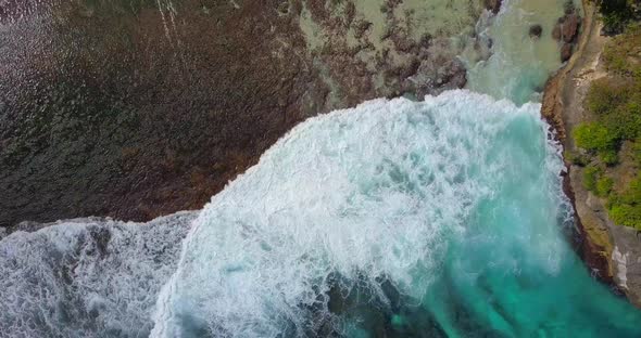Aerial drone view of a coral reef and waves at the beach.